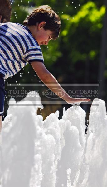 Мальчик играет с водой в фонтане / Люди / дети и подростки