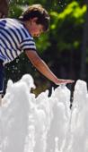 Мальчик играет с водой в фонтане