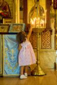 Православие. Девочка в церкви зажигает свечку.